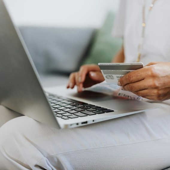 pexels-photo-4968391-4968391 Close-up of a person holding a credit card while shopping online using a laptop at home.